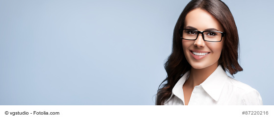 Portrait of happy smiling brunette businesswoman in glasses, over grey background